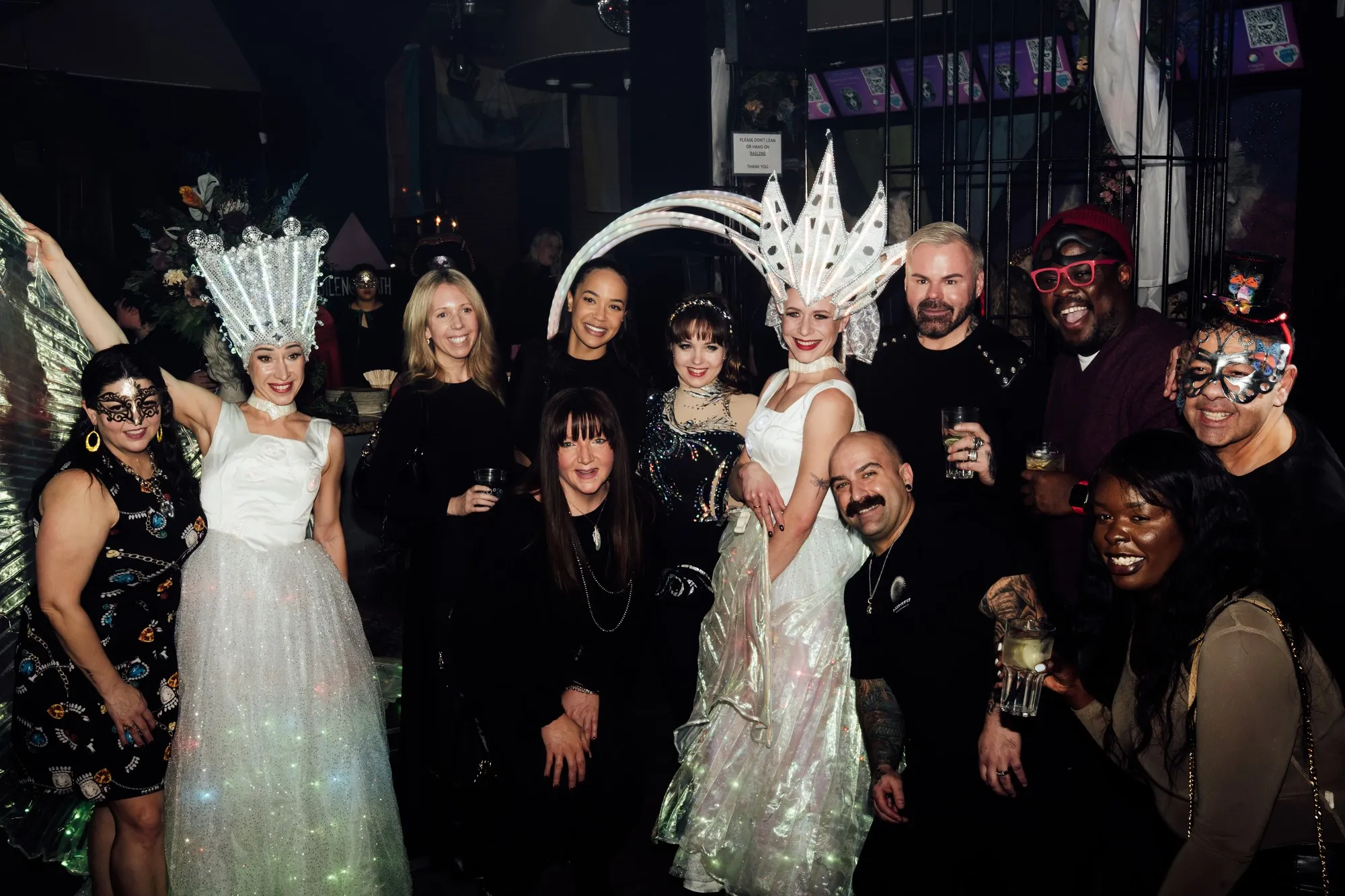 Guests in crystal headdresses and masquerade costumes gathered on a nightclub dance floor